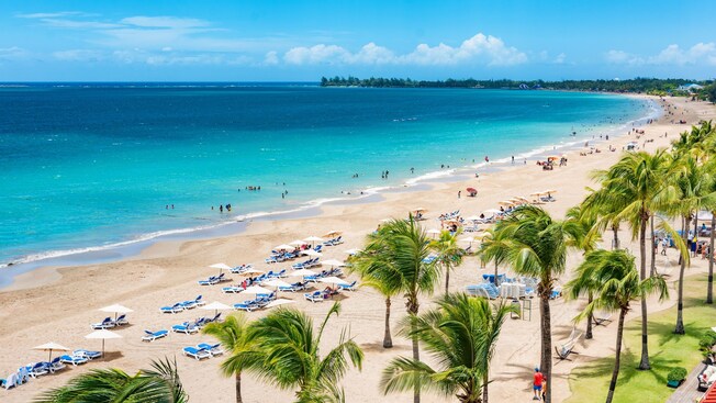 Guests playing in the surf and relaxing on the sand at Isla Verde Beach in Puerto Rico