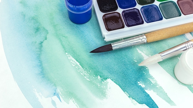 Pinceles y una caja de pinturas sobre una pintura de acuarela Pinceles y una caja de pinturas sobre una pintura de acuarela