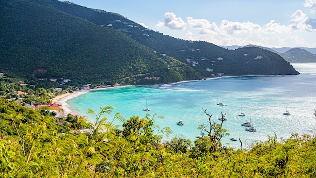 Boats moored in a tropical bay surrounded by hills with lush vegetation