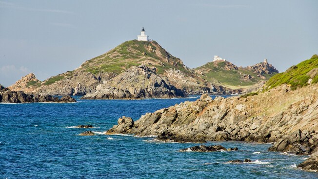 A lighthouse perched on a hilltop overlooking the rocky coastline and ocean