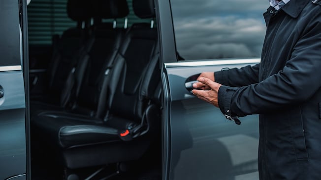 A man opening the door to a van with empty seats inside A man opening the door to a van with empty seats inside