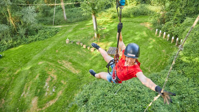 A woman reaching out for a rope while zip lining in Amsterdam