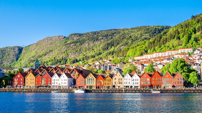 Waterfront buildings lining the shoreline in front of a large mountain range Waterfront buildings lining the shoreline in front of a large mountain range