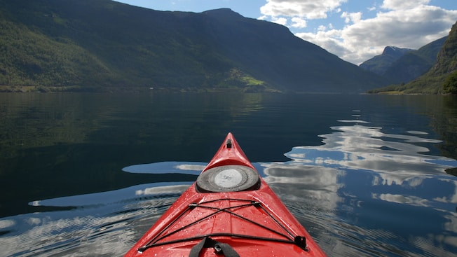 A kayak on calm fjord waters surrounded by mountains in Bergen, Norway A kayak on calm fjord waters surrounded by mountains in Bergen, Norway