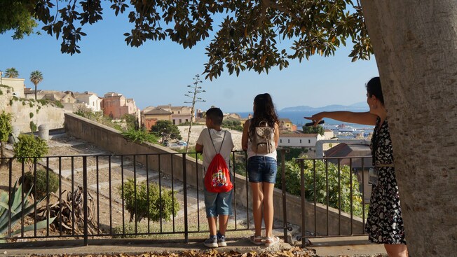 Two children standing at a scenic overlook viewing Cagliari's historic architecture
