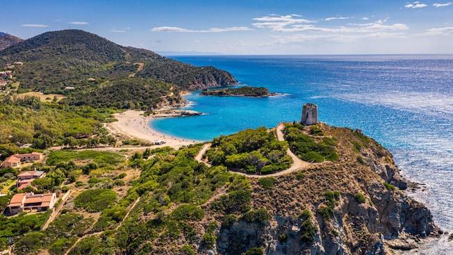 A coastal village in Cagliari, Italy on a hillside peninsula near a beach A coastal village in Cagliari, Italy on a hillside peninsula near a beach