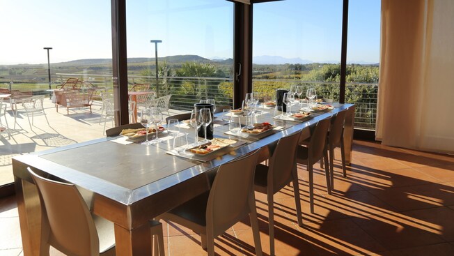 Una mesa preparada para una degustación de vinos con vistas a la campiña de Cerdeña