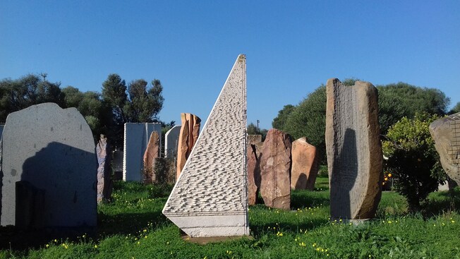 An outdoor garden with a collection of tall stone sculptures of various shapes