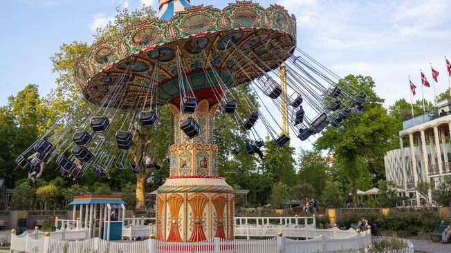 An ornate swing carousel in motion at Tivoli Gardens amusement park in Copenhagen, Denmark