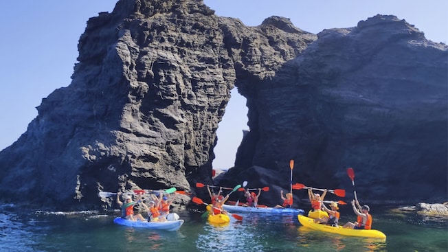 Kayakistas levantando sus remos en triunfo cerca de una formación rocosa natural en Cartagena, España Kayakistas levantando sus remos en triunfo cerca de una formación rocosa natural en Cartagena, España