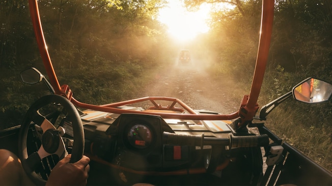 Two Guests in a dune buggy driving on a dirt path through the woods Two Guests in a dune buggy driving on a dirt path through the woods