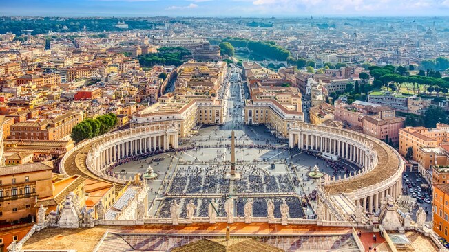 Saint Peter’s Square, featuring 2 fountains and a tall central obelisk, surrounded by columns