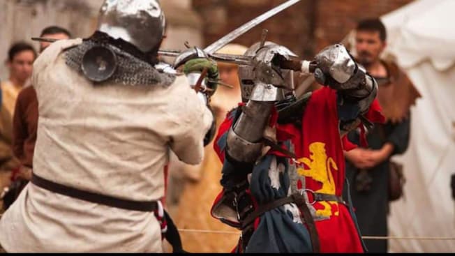 Two men dressed as knights fighting with swords Two men dressed as knights fighting with swords