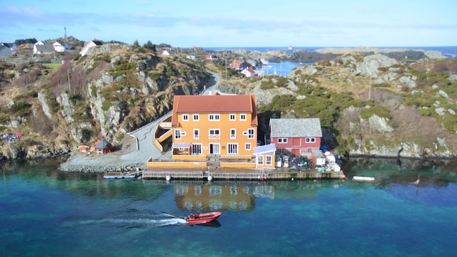 A boat cruising through a channel past a hotel on the island of Røvær A boat cruising through a channel past a hotel on the island of Røvær