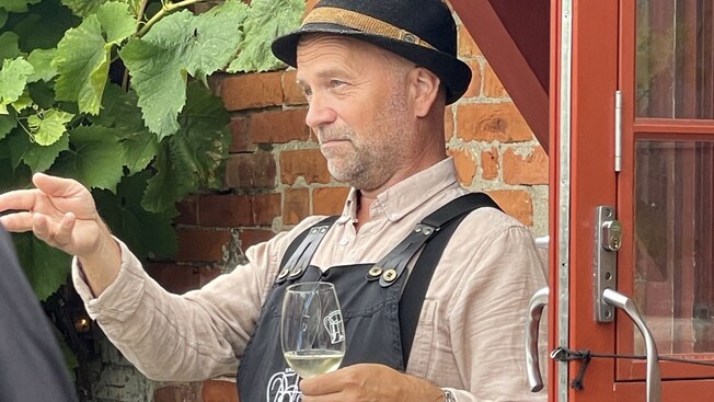 Guía de degustación de vinos con sombrero alpino y una copa de vino en la mano