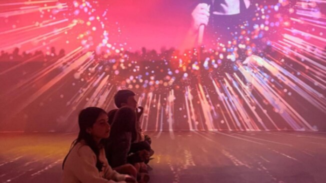 Guests sitting on a floor watching a projected performance of a Fado singer
