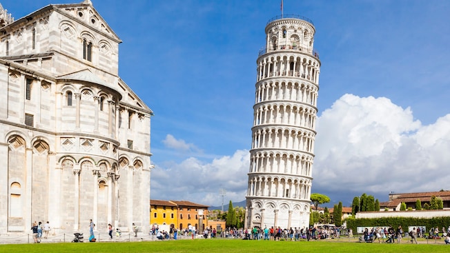 The Leaning Tower of Pisa beside a cathedral with people walking nearby The Leaning Tower of Pisa beside a cathedral with people walking nearby