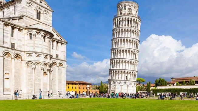 The Leaning Tower of Pisa beside a cathedral with people walking nearby
