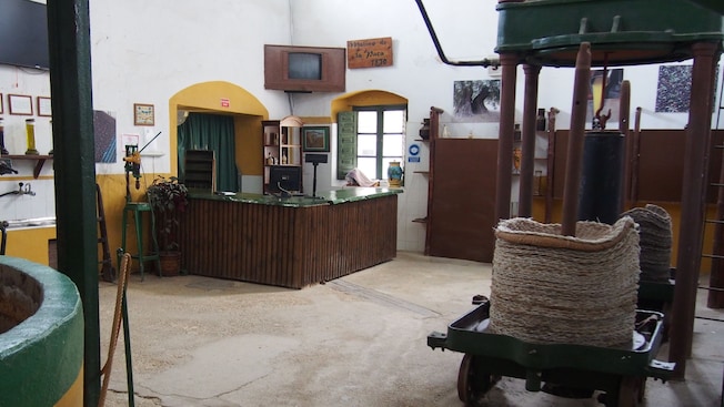 A room in an olive mill containing a business counter, an olive press and olive oil making machinery A room in an olive mill containing a business counter, an olive press and olive oil making machinery