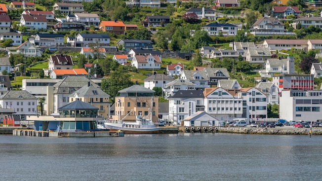 A waterfront town with homes on a hillside and a boat docked at the harbor A waterfront town with homes on a hillside and a boat docked at the harbor