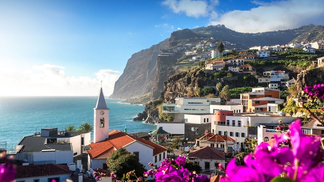 Câmara de Lobos village nesting against a rocky coastline featuring Igreja de São Sebastião with the ocean extending to the horizon Câmara de Lobos village nesting against a rocky coastline featuring Igreja de São Sebastião with the ocean extending to the horizon