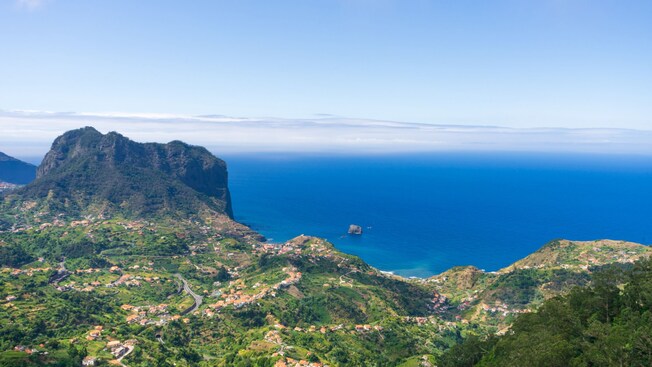 A coastal landscape with hills, scattered houses and a steep cliff overlooking the ocean