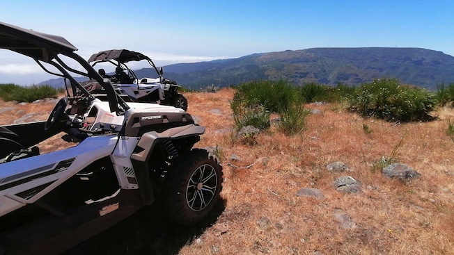 A pair of off road buggies parked on a ridge with a view of the Cabo Girao mountains A pair of off road buggies parked on a ridge with a view of the Cabo Girao mountains