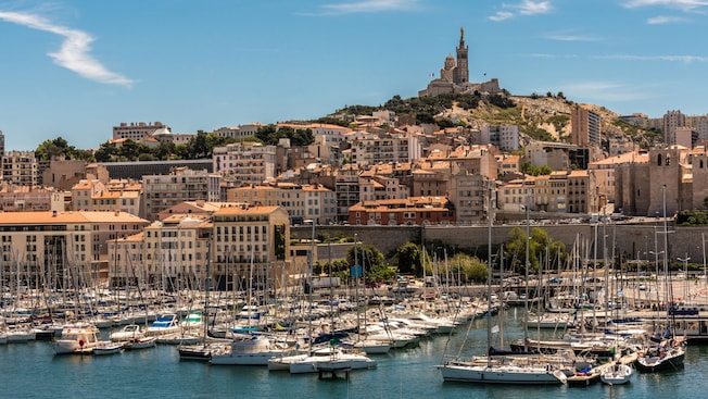 A marina and the Notre-Dame de la Garde basilica on top of a hill in Marseille, France A marina and the Notre-Dame de la Garde basilica on top of a hill in Marseille, France
