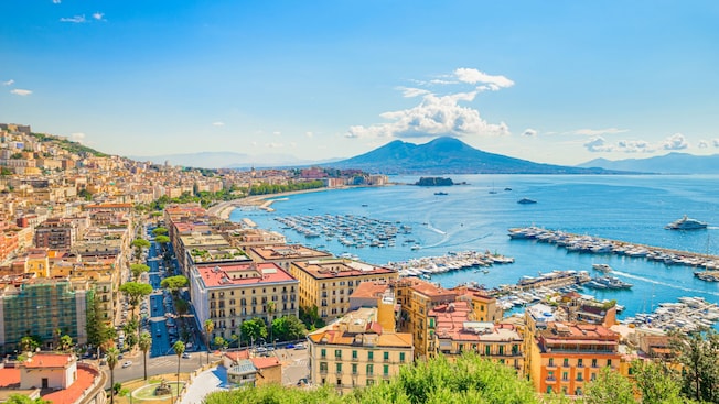 The harbor of Naples with moored boats surrounded by a hilly landscape filled with buildings The harbor of Naples with moored boats surrounded by a hilly landscape filled with buildings