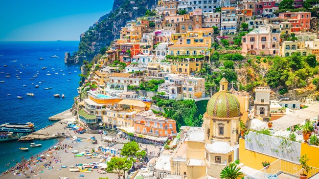 A hilly, seaside town on the Amalfi Coast, with a busy beach and bustling harbor