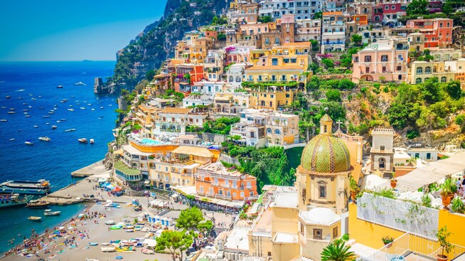 A hilly, seaside town on the Amalfi Coast, with a busy beach and bustling harbor