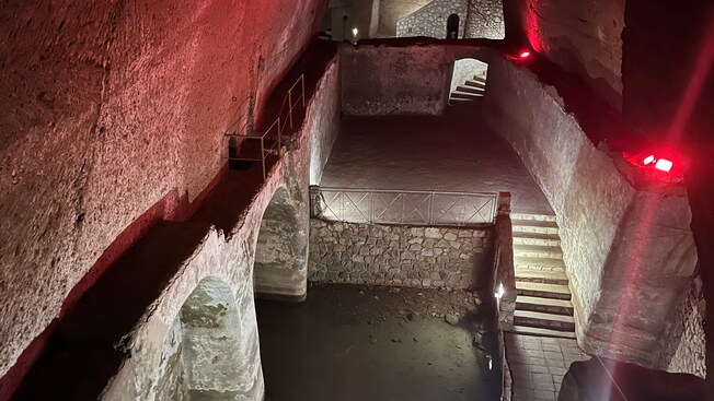 Underground chamber with stone walkways, staircases and arched walls connected by multiple levels