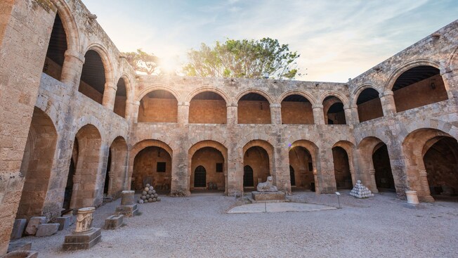 Historic stone courtyard with arched walkways and scattered artifacts