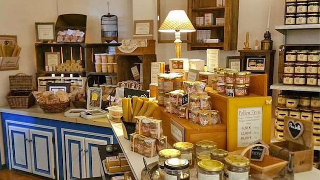 El interior de una tienda en la que se exhiben frascos de miel y productos empaquetados dispuestos en estantes y mesas El interior de una tienda en la que se exhiben frascos de miel y productos empaquetados dispuestos en estantes y mesas