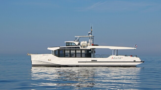 A passenger boat with a French flag sailing on serene waters