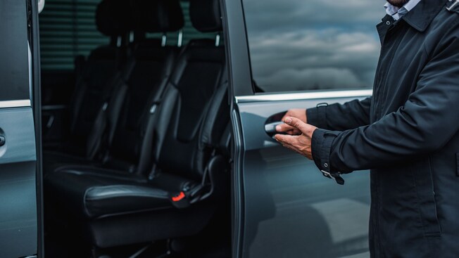 A driver opening the door to a private minibus