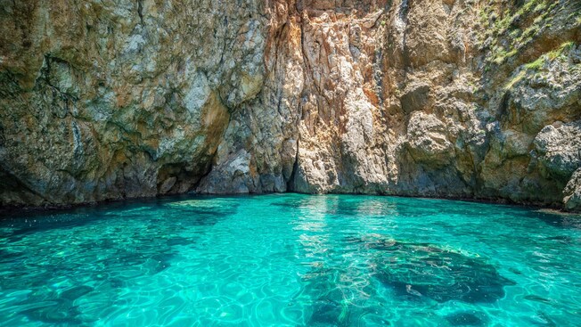A body of water inside of a rocky inlet with rugged cliff walls