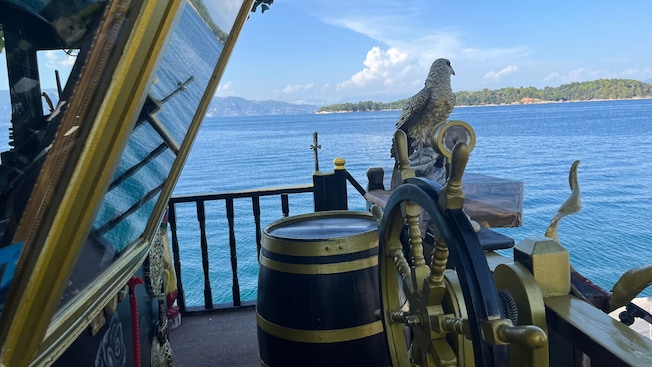 View from the deck of a pirate ship with a wheel and an eagle statue overlooking the sea View from the deck of a pirate ship with a wheel and an eagle statue overlooking the sea