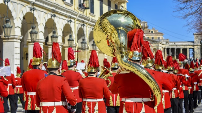 A marching band in matching uniforms, helmets and plumes, carrying brass instruments A marching band in matching uniforms, helmets and plumes, carrying brass instruments