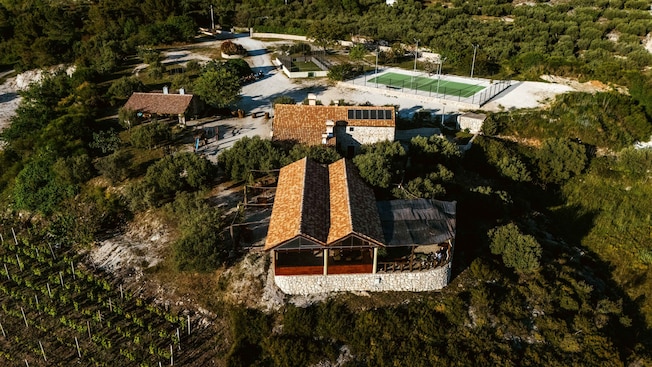 A building with a tennis court surrounded by the lush Croatian countryside A building with a tennis court surrounded by the lush Croatian countryside