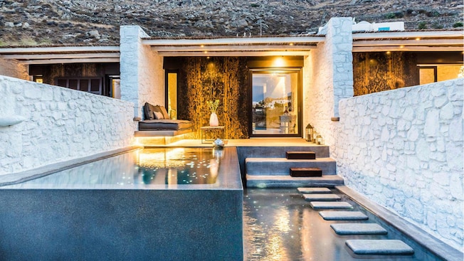 A seated area next to a pool near a cabana in Mykonos, Greece A seated area next to a pool near a cabana in Mykonos, Greece