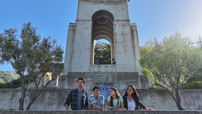 A boy and a girl posing next to their parents in front of a structure at the Wrigley Memorial and Botanic Garden on Santa Catalina Island, California