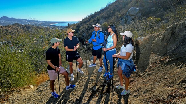 Un guía hablando con cuatro Visitantes mientras están de pie en una ladera durante una caminata