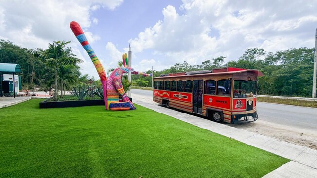 A classic trolley car parked on the curb beside a sculpture