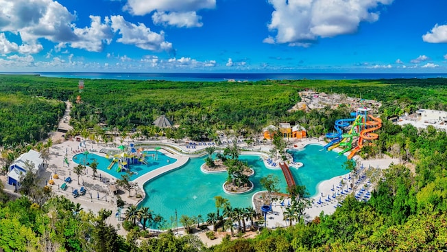 Aerial view of Kuzá Beach & Adventure Park featuring large pools, colorful waterslides and lush jungle scenery