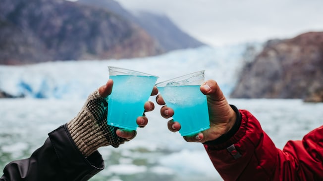 Duas pessoas brindando com bebidas geladas perto da calota polar de Stikine, no Alasca Duas pessoas brindando com bebidas geladas perto da calota polar de Stikine, no Alasca
