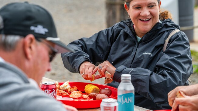 Three Guests enjoying a seafood feast featuring crab, shrimp, corn on the cob and potatoes