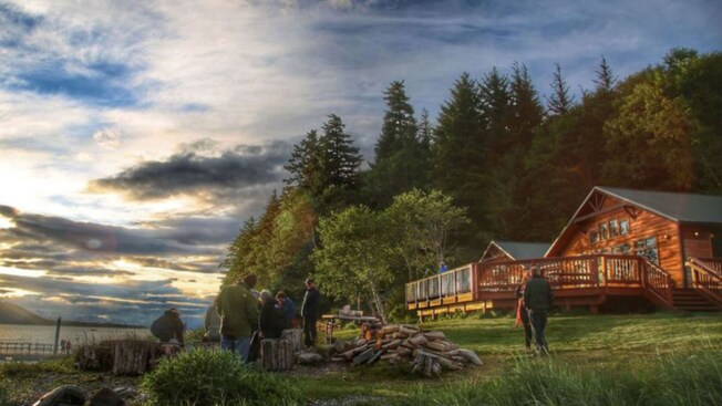 A rendering of a group of people sitting on logs outside Orca Point Lodge