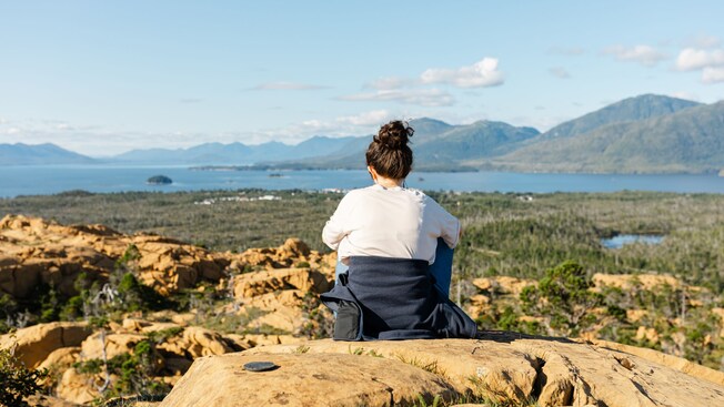 Una mujer sentada en la cima de una colina con vista a un cuerpo de agua en Yellow Hill