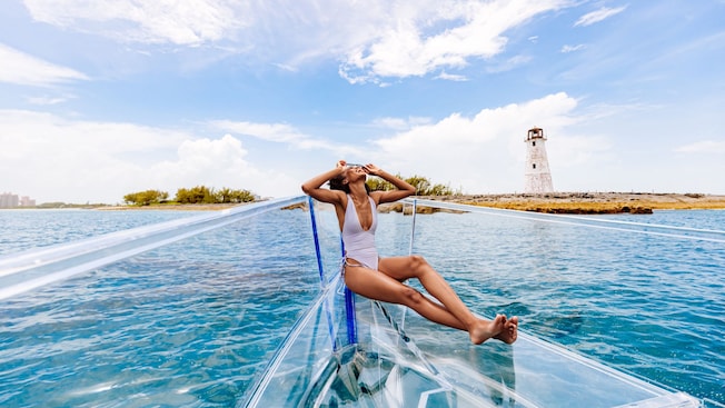 A woman relaxing at the bow of a clear boat at sea A woman relaxing at the bow of a clear boat at sea